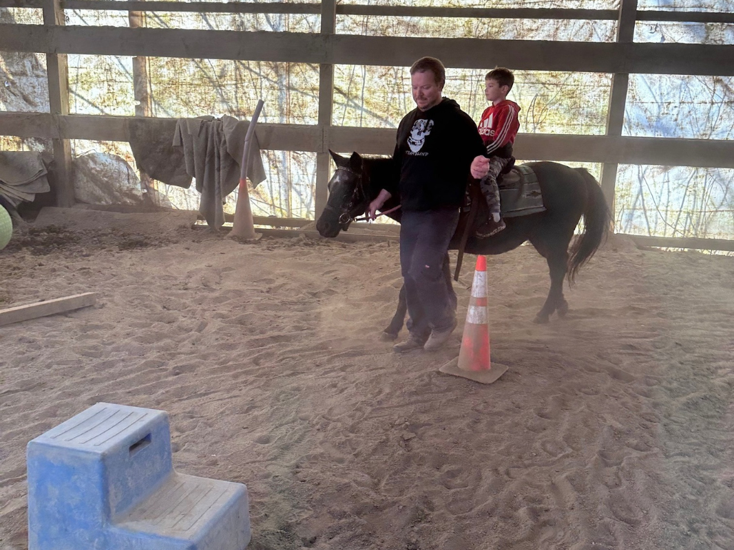 A man skillfully navigates a horse within the confines of an indoor arena