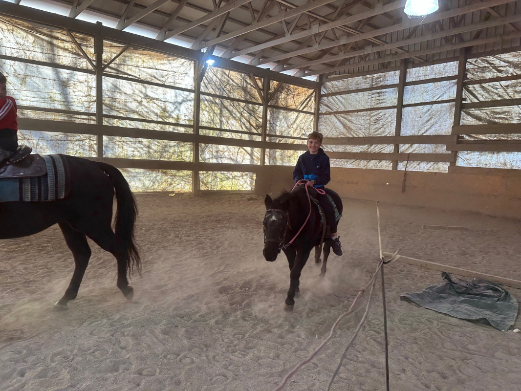 Two young riders on horseback in an indoor arena